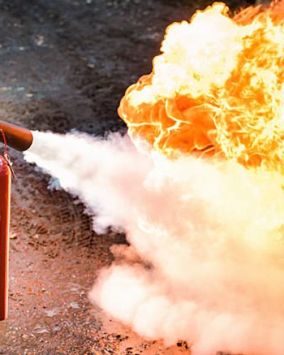 A man using a carbon dioxide fire extinguisher to fight a fire.